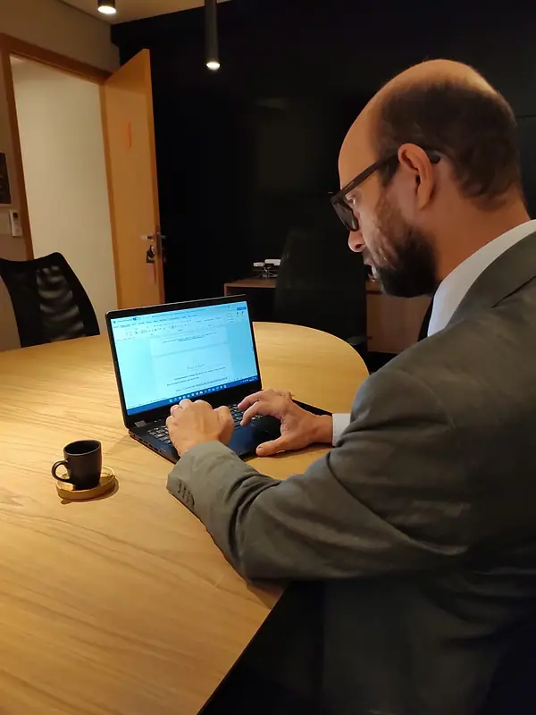 Bruno de Bruno trabalhando no notebook, sentado à mesa do escritório