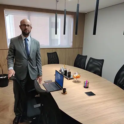 Bruno de Bruno em pé ao lado da mesa de reuniões do escritório