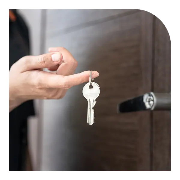 Mão segurando a chave de um imóvel diante da porta