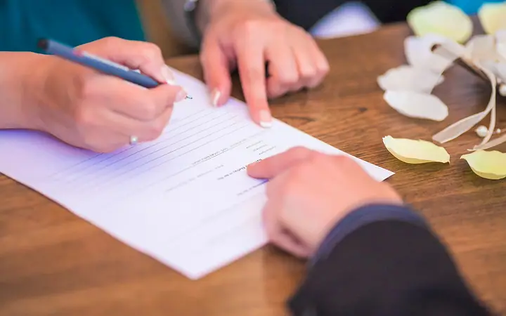 Duas pessoas assinando um documento sobre a mesa